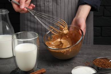 Photo of Woman whipping cream for dalgona coffee at grey table, closeup