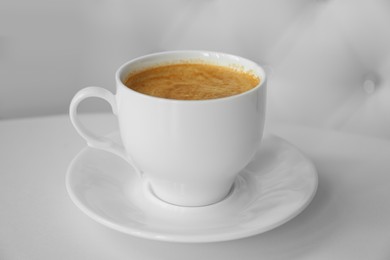 Photo of Cup of delicious aromatic coffee on white table indoors, closeup