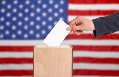 Election in USA. Woman putting her vote into ballot box against national flag of United States, closeup