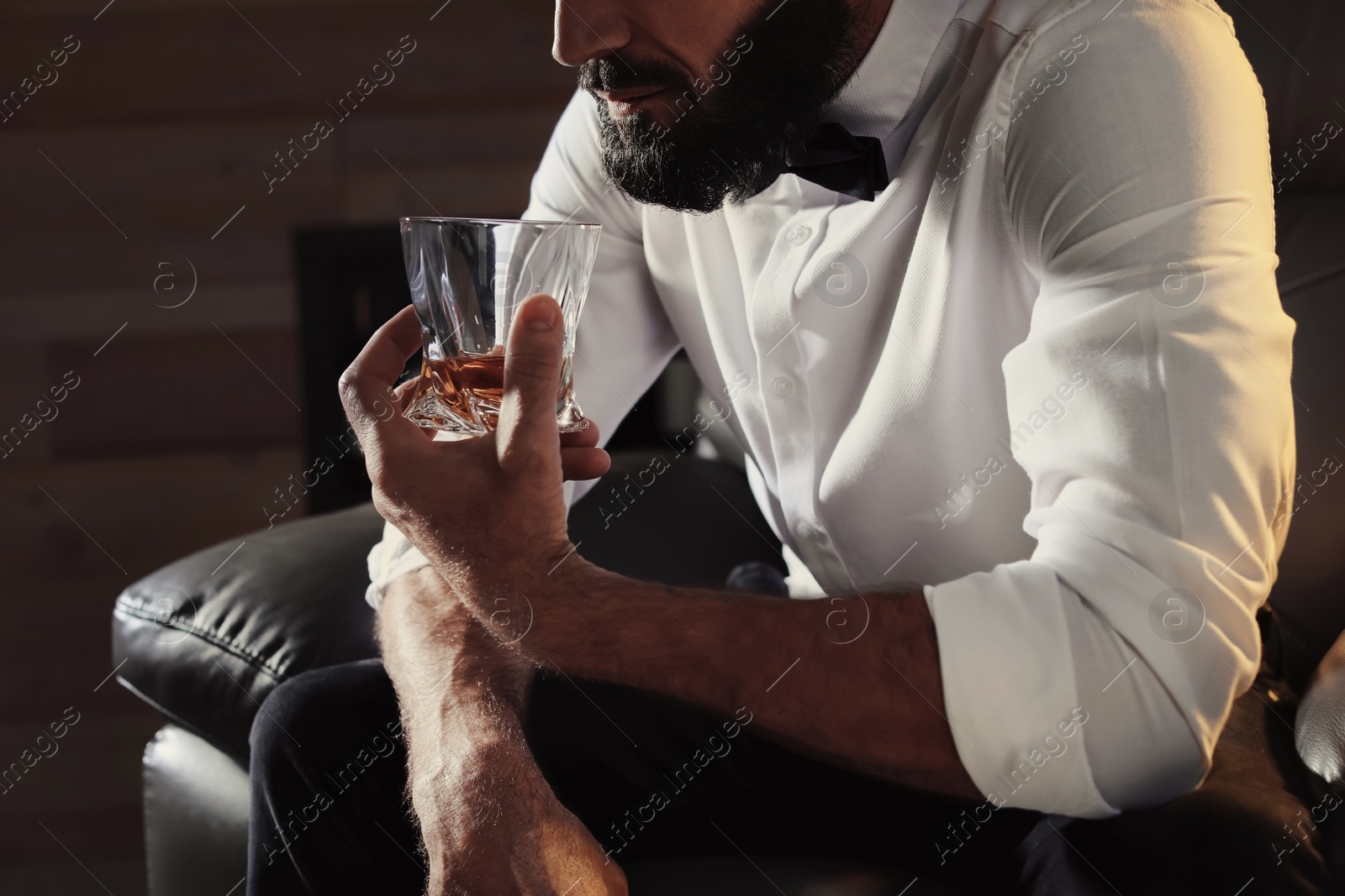 Photo of Man with glass of whiskey sitting in armchair, closeup