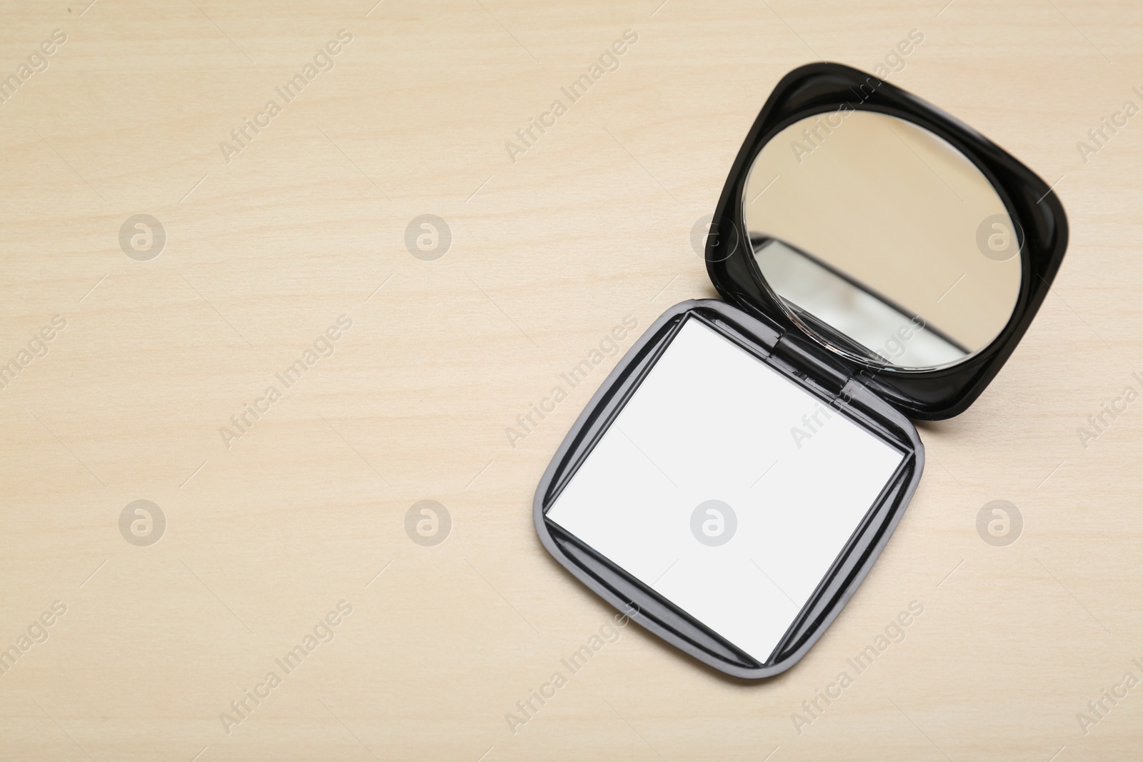 Photo of Stylish cosmetic pocket mirror on wooden table, top view. Space for text