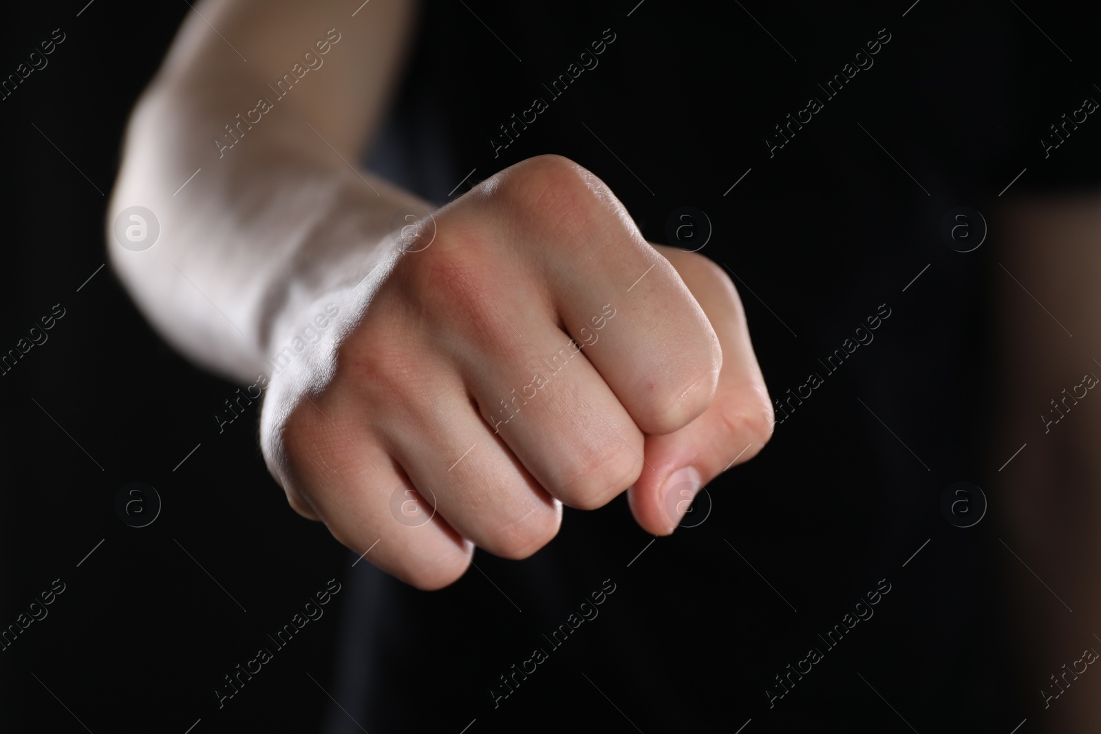 Photo of Man showing fist with space for tattoo on black background, selective focus