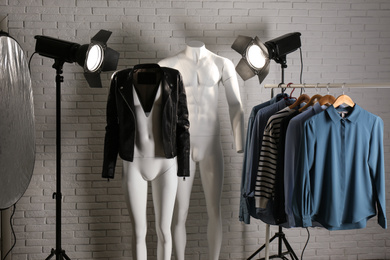 Stylish clothes on ghost mannequin and professional lighting equipment in modern studio. Fashion photography