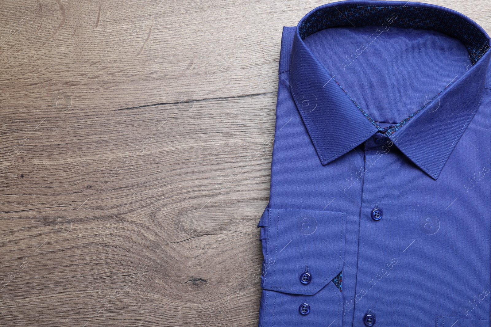 Photo of Stylish blue shirt on wooden table, top view with space for text. Dry-cleaning service