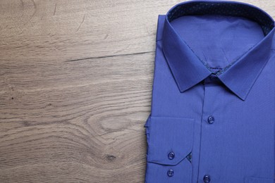 Photo of Stylish blue shirt on wooden table, top view with space for text. Dry-cleaning service