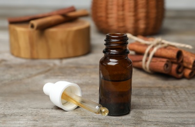 Photo of Closeup of bottle with cinnamon oil on wooden table