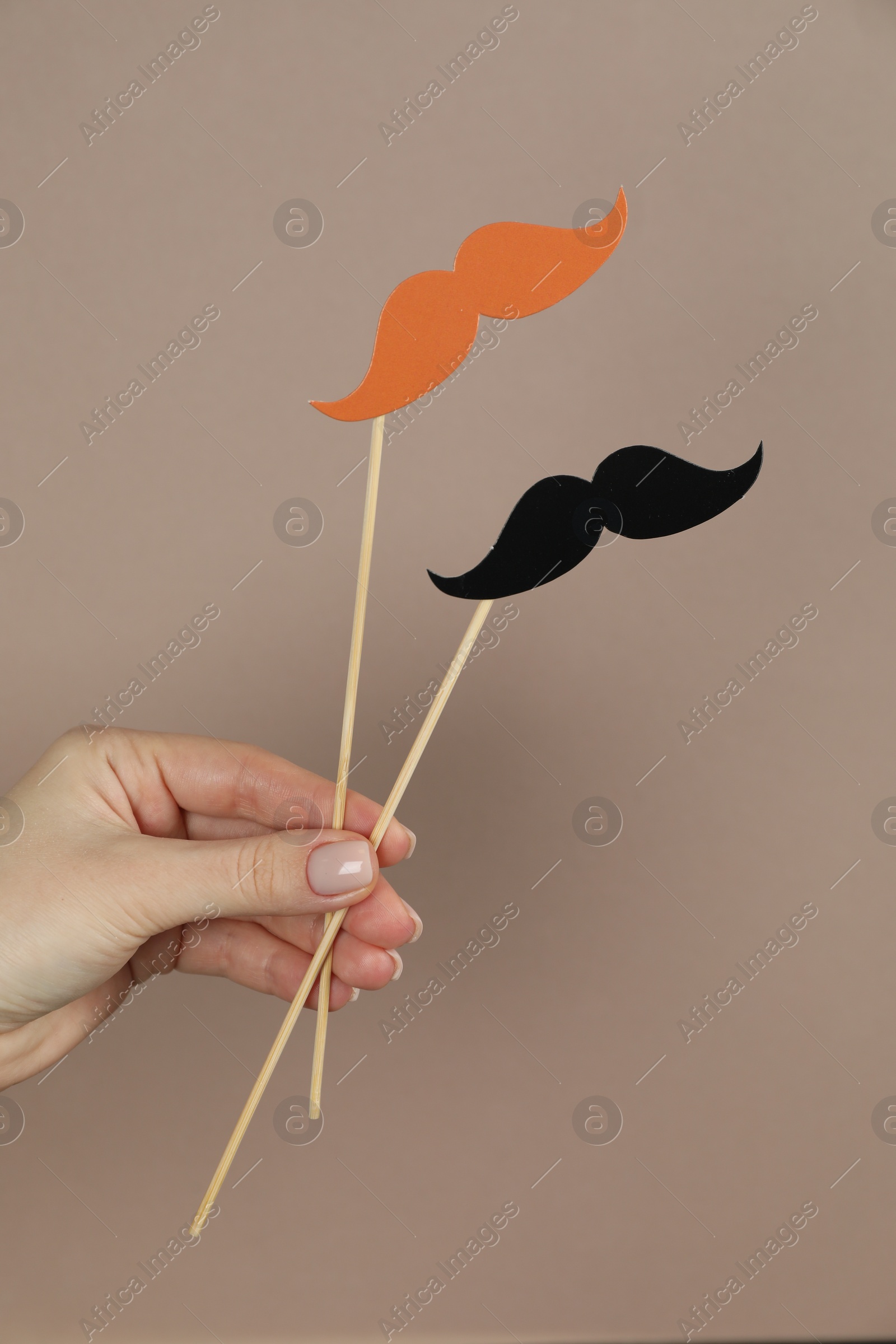Photo of Woman with fake paper mustaches on beige background, closeup