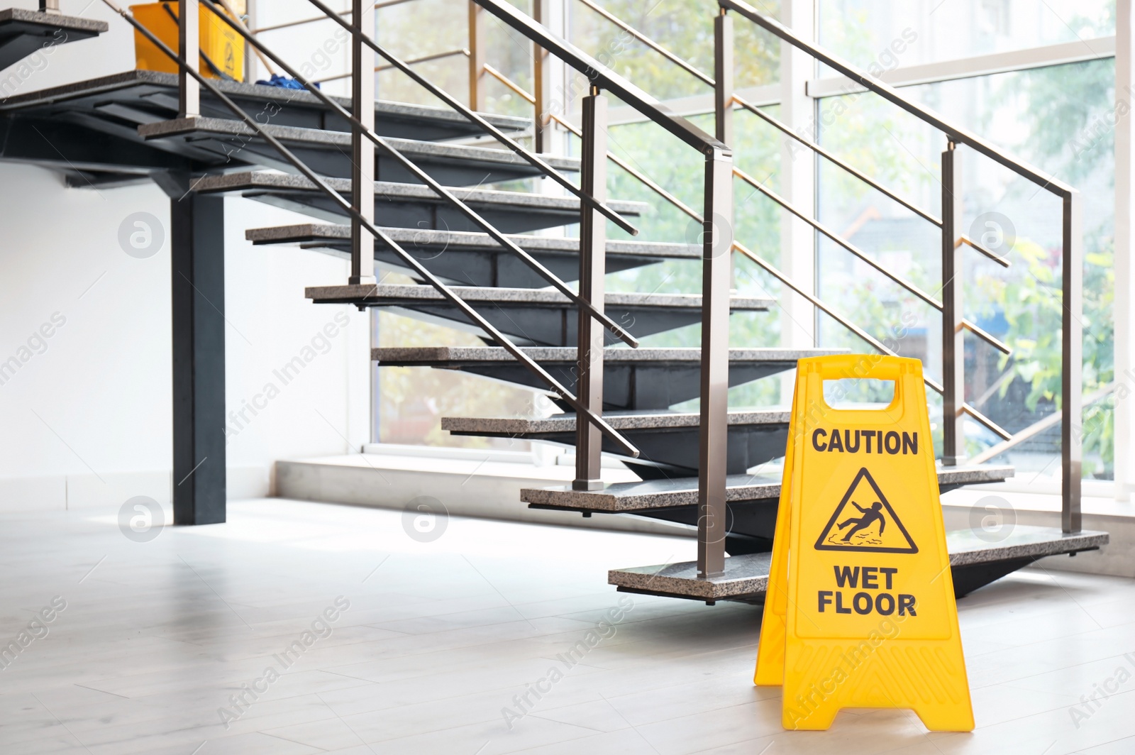 Photo of Safety sign with phrase Caution wet floor near stairs