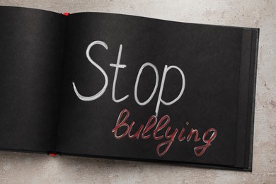 Photo of Open notebook with phrase Stop Bullying on white table, top view