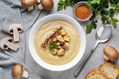 Photo of Delicious cream soup with mushrooms and croutons on beige textured table, flat lay