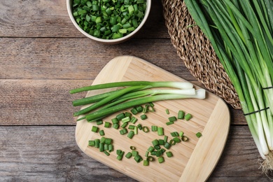 Flat lay composition with fresh green onions on wooden background