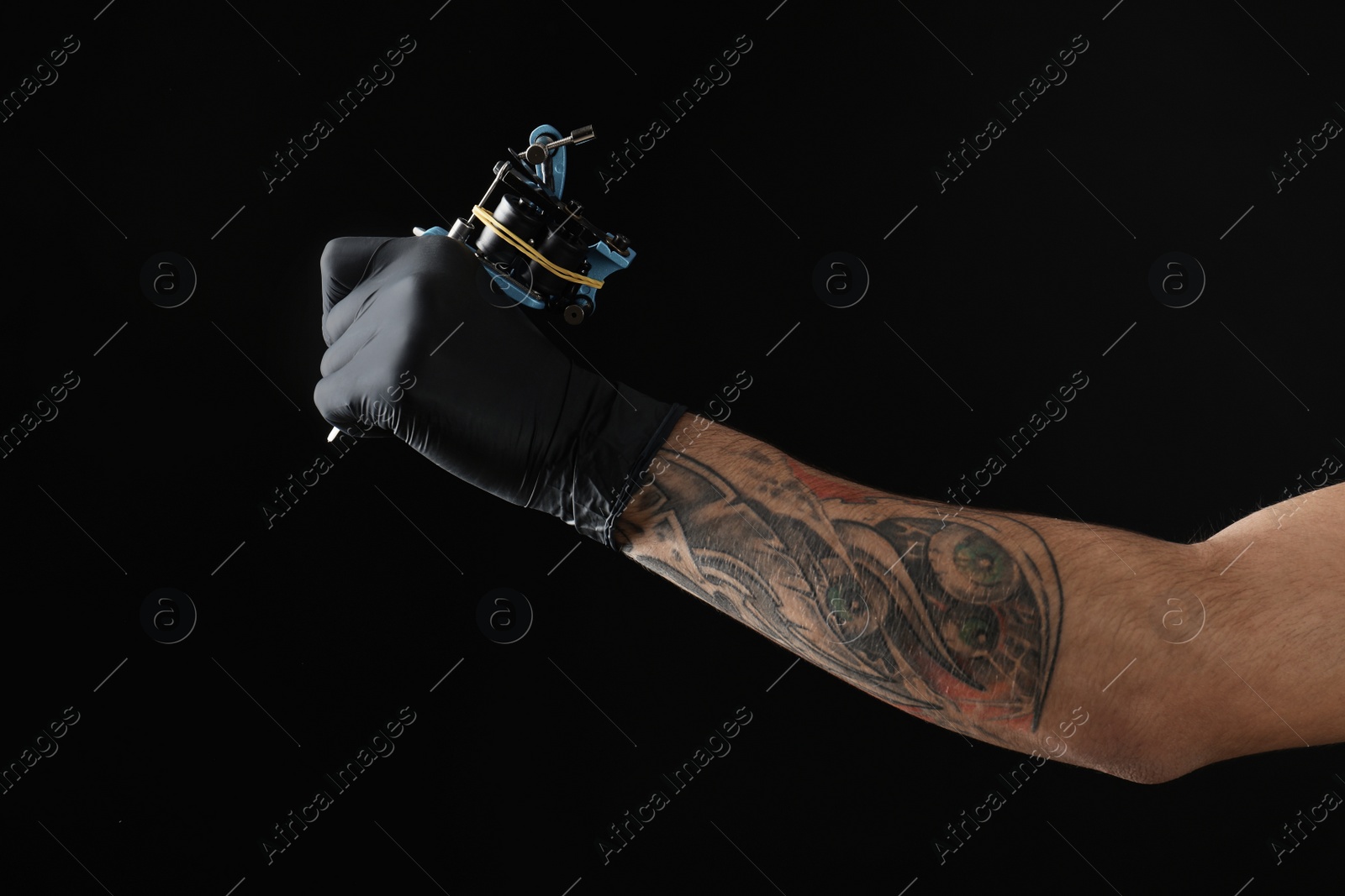 Photo of Professional tattoo artist with machine on black background, closeup