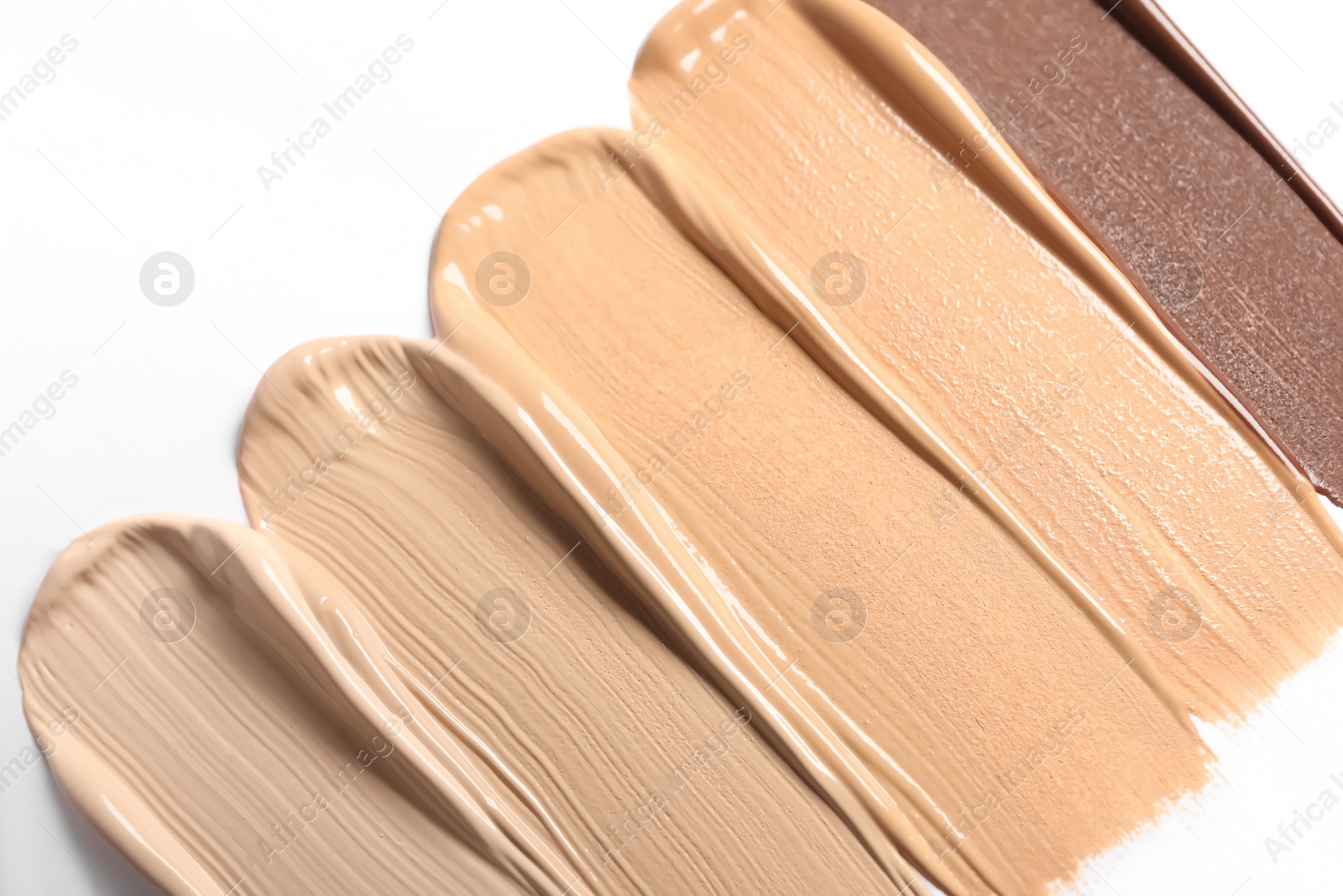 Photo of Samples of skin foundation on white background, closeup