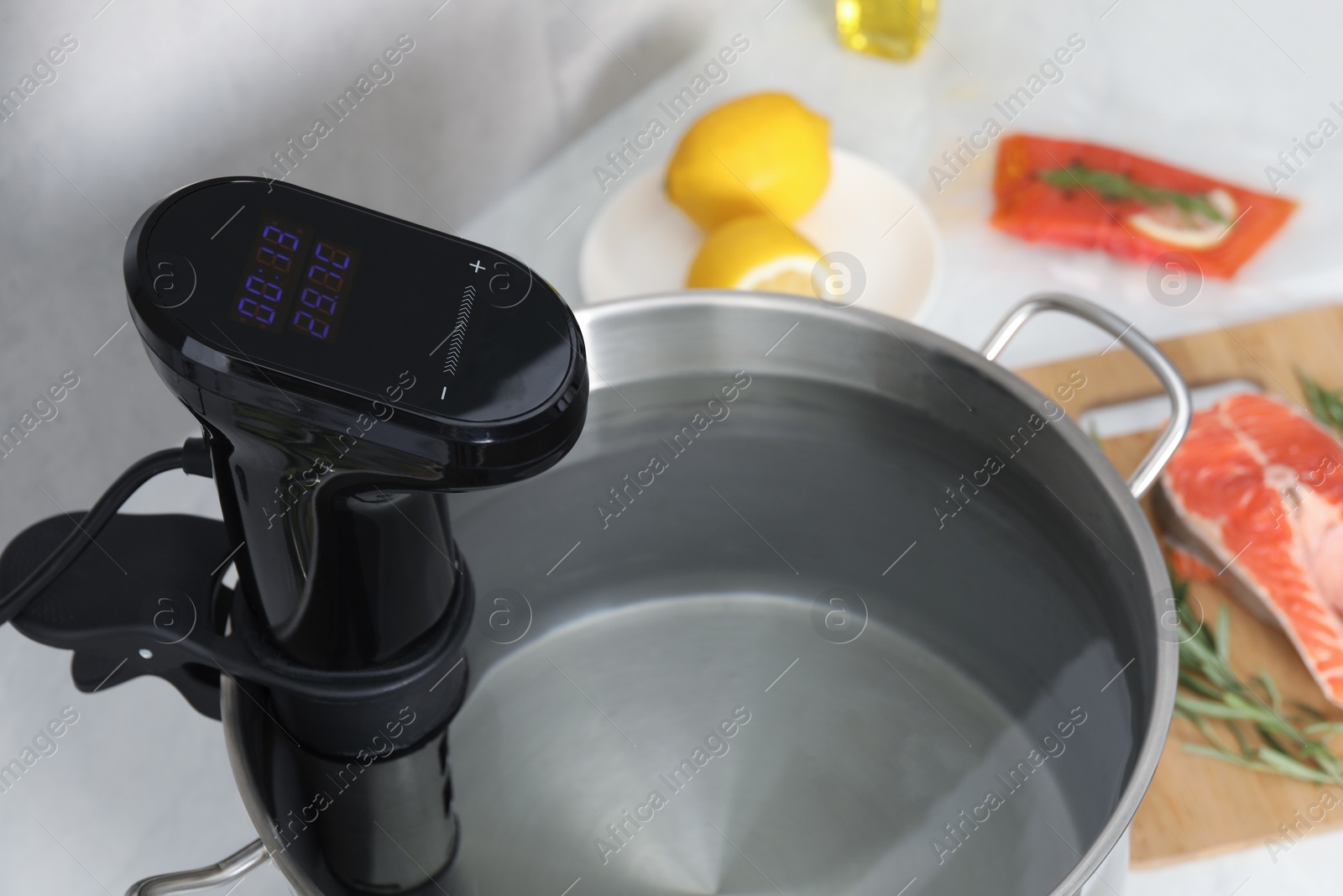 Photo of Sous vide cooker in pot on white table, closeup. Thermal immersion circulator