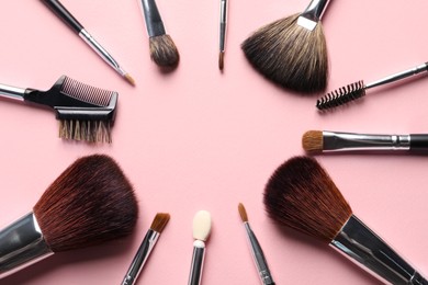 Frame of different makeup brushes on pink background, flat lay. Space for text