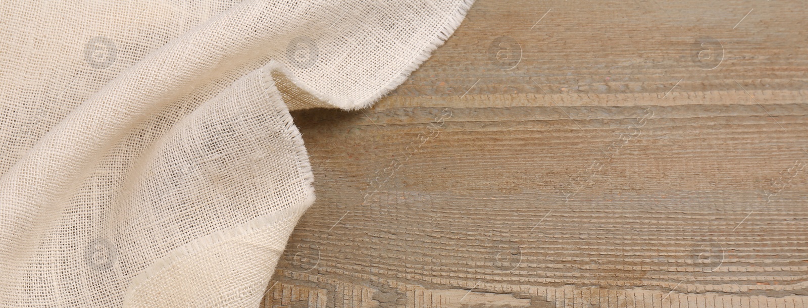 Photo of Beige burlap fabric on wooden table, above view. Space for text