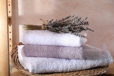 Photo of Stacked soft towels and lavender on wooden shelf indoors
