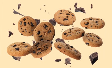 Image of Delicious chocolate chip cookies and pieces of chocolate falling on beige background