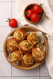 Fresh delicious puff pastry with tasty filling and tomatoes on white tiled surface, flat lay