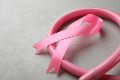 Photo of Pink ribbon and stethoscope on grey background, space for text. Breast cancer concept