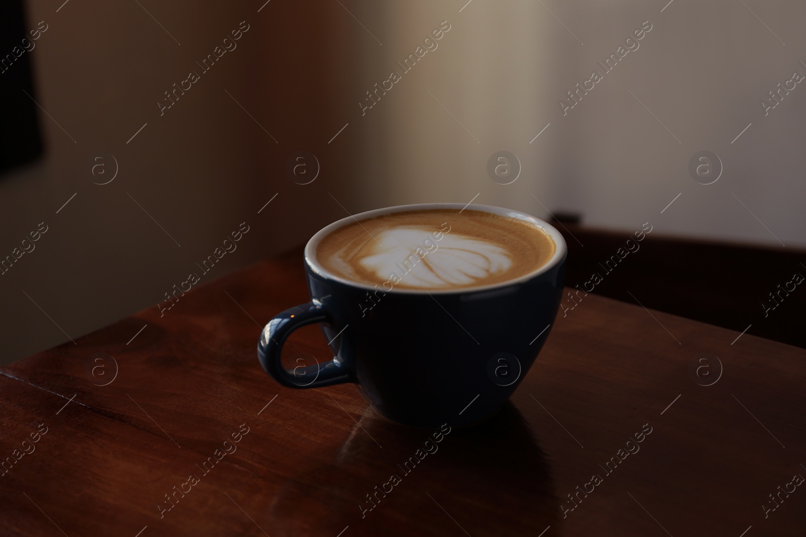 Photo of Cup of aromatic coffee on wooden table in cafe