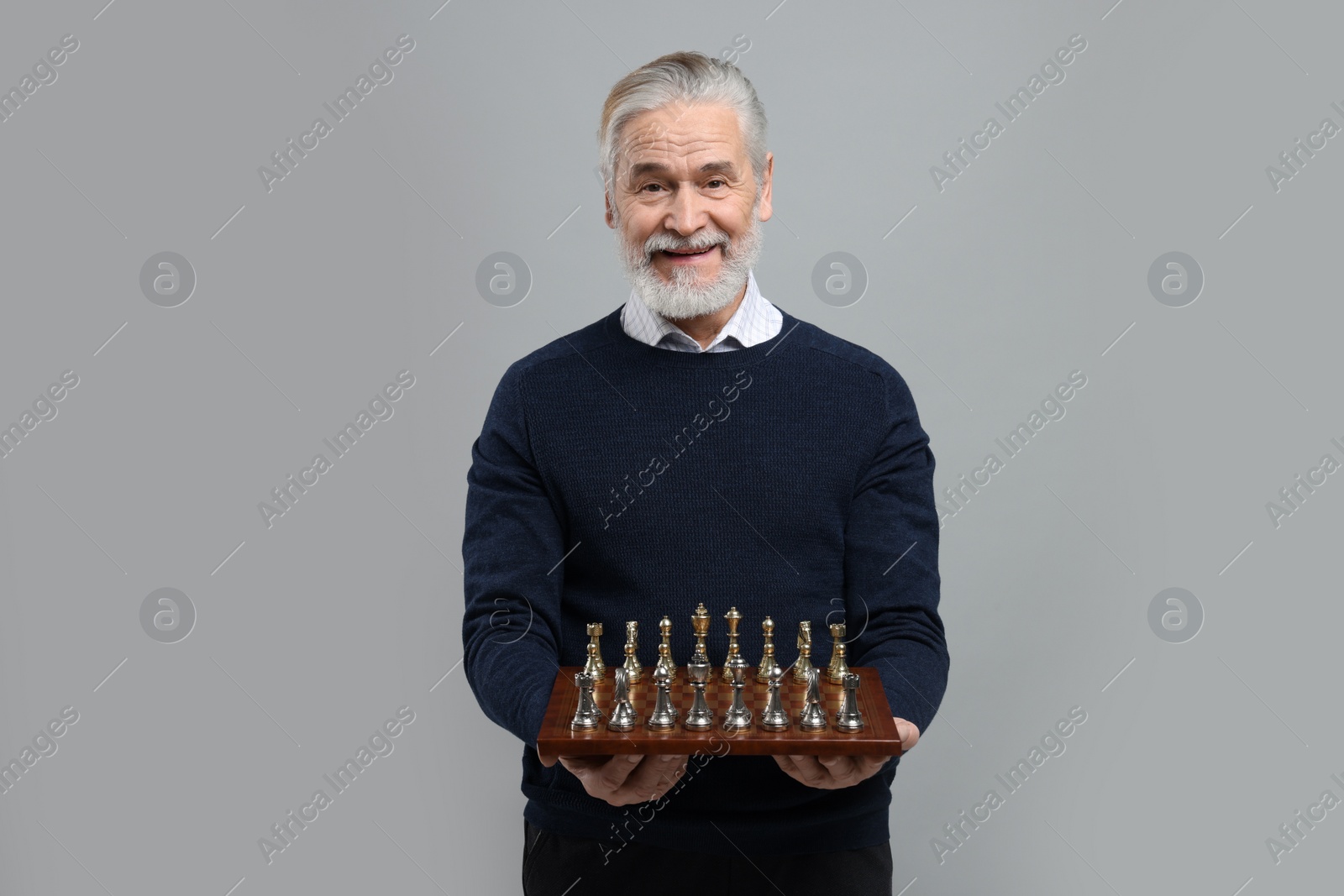 Photo of Man with chessboard and game pieces on light gray background