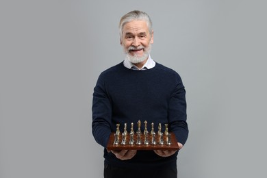 Photo of Man with chessboard and game pieces on light gray background