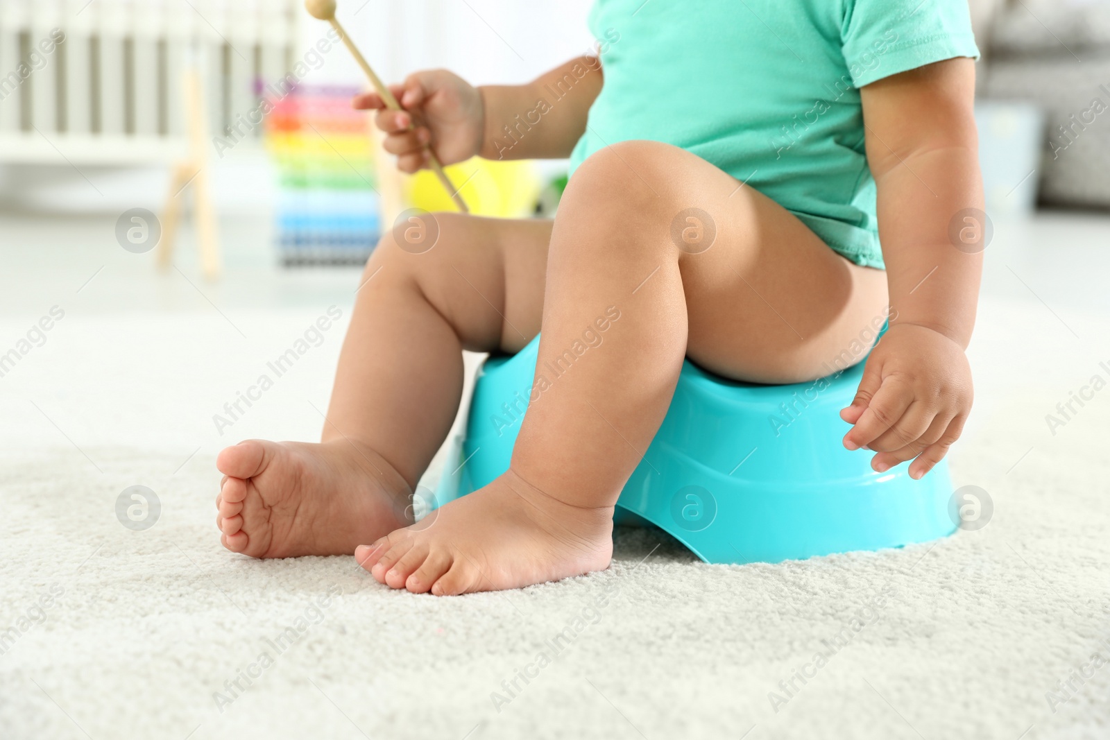 Photo of Little boy with wooden stick sitting on potty at home, closeup