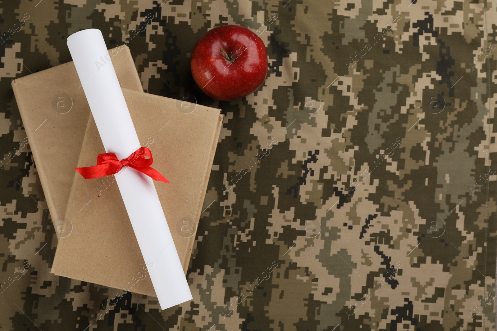 Photo of Books, apple and diploma on camouflage background, flat lay with space for text. Military education concept