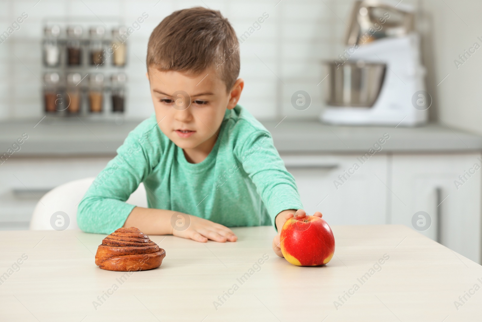 Photo of Little boy with pastry and apple at home. Diabetes diet