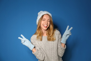 Image of Happy young woman wearing warm sweater, knitted hat and mittens on blue background 