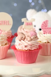 Beautifully decorated baby shower cupcakes for girl with cream and toppers on stand
