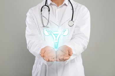 Doctor and illustration of female reproductive system on grey background, closeup