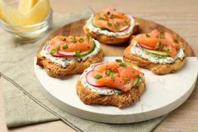 Photo of Tasty canapes with salmon, cucumber, radish and cream cheese on wooden table