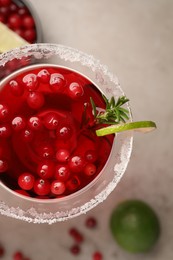 Photo of Tasty cranberry cocktail with rosemary and lime in glass on grey table, flat lay