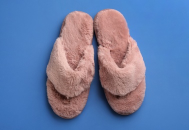 Pair of stylish soft slippers on blue background, flat lay