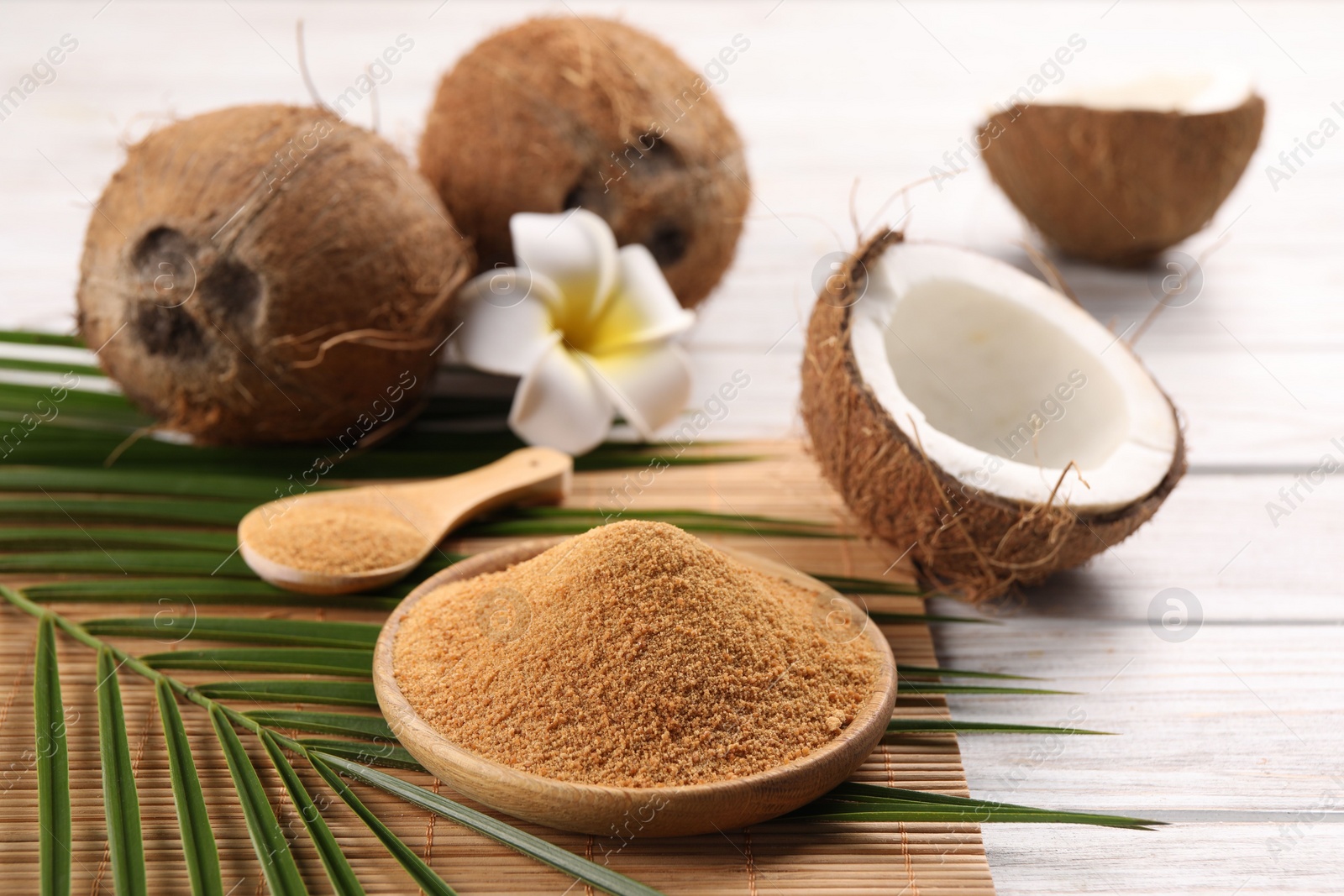 Photo of Coconut sugar, palm leaves, fruits and bamboo mat on wooden rustic table, closeup