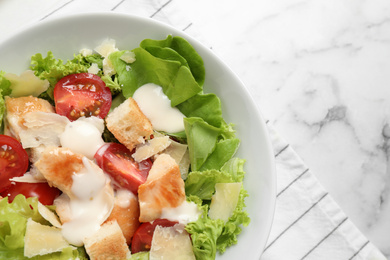 Photo of Tasty Caesar salad on white marble table, top view