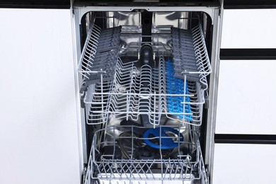 Photo of Open clean empty dishwasher indoors. Home appliance