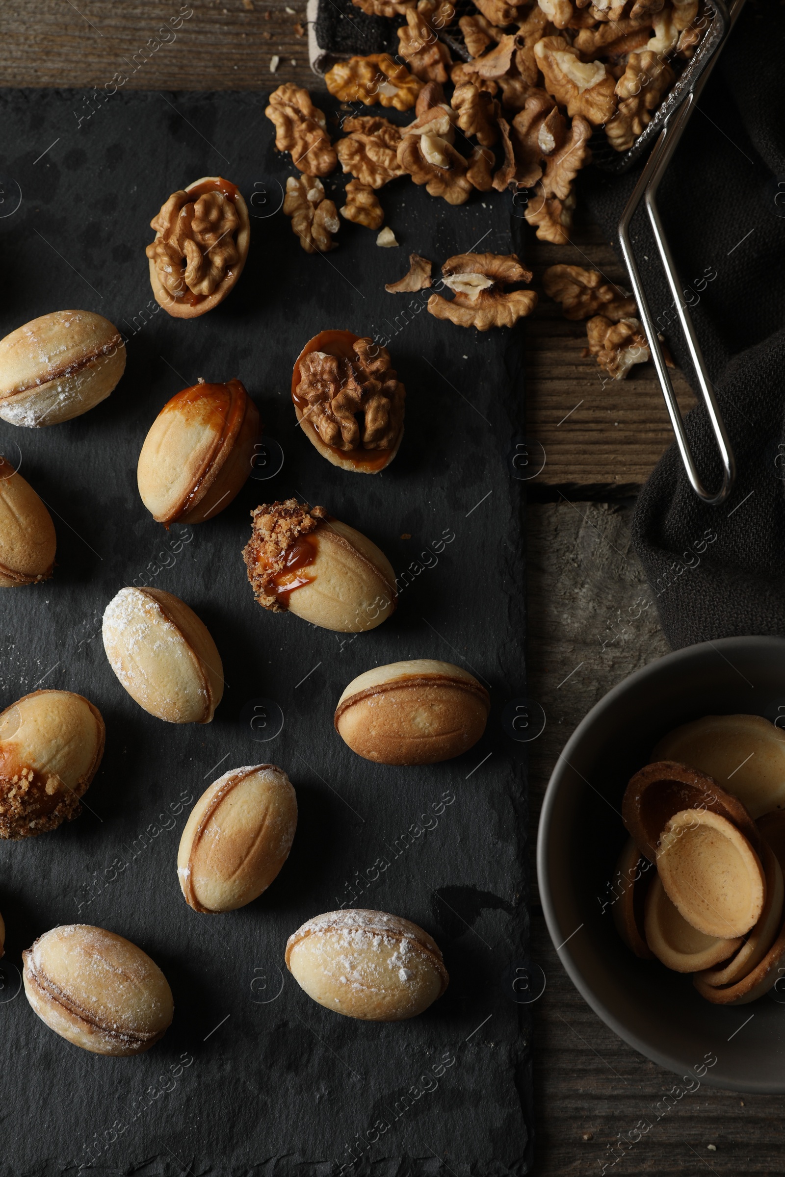 Photo of Freshly baked homemade walnut shaped cookies and nuts on wooden table, flat lay