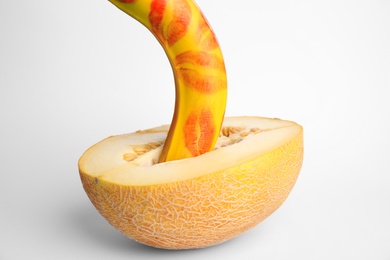 Fresh banana with red lipstick marks and melon on white background. Sex concept