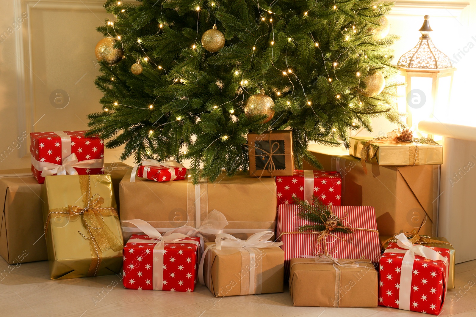 Photo of Gift boxes under Christmas tree with fairy lights indoors