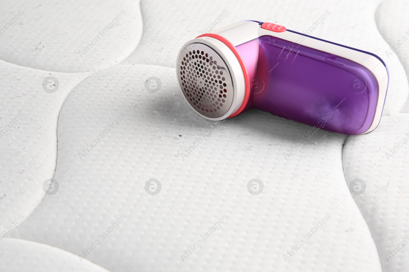 Photo of Fabric shaver on mattress with lint. Space for text