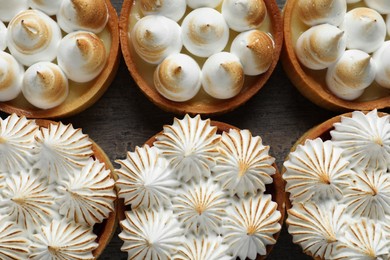 Photo of Many different tartlets with meringue on dark grey table, flat lay. Tasty dessert