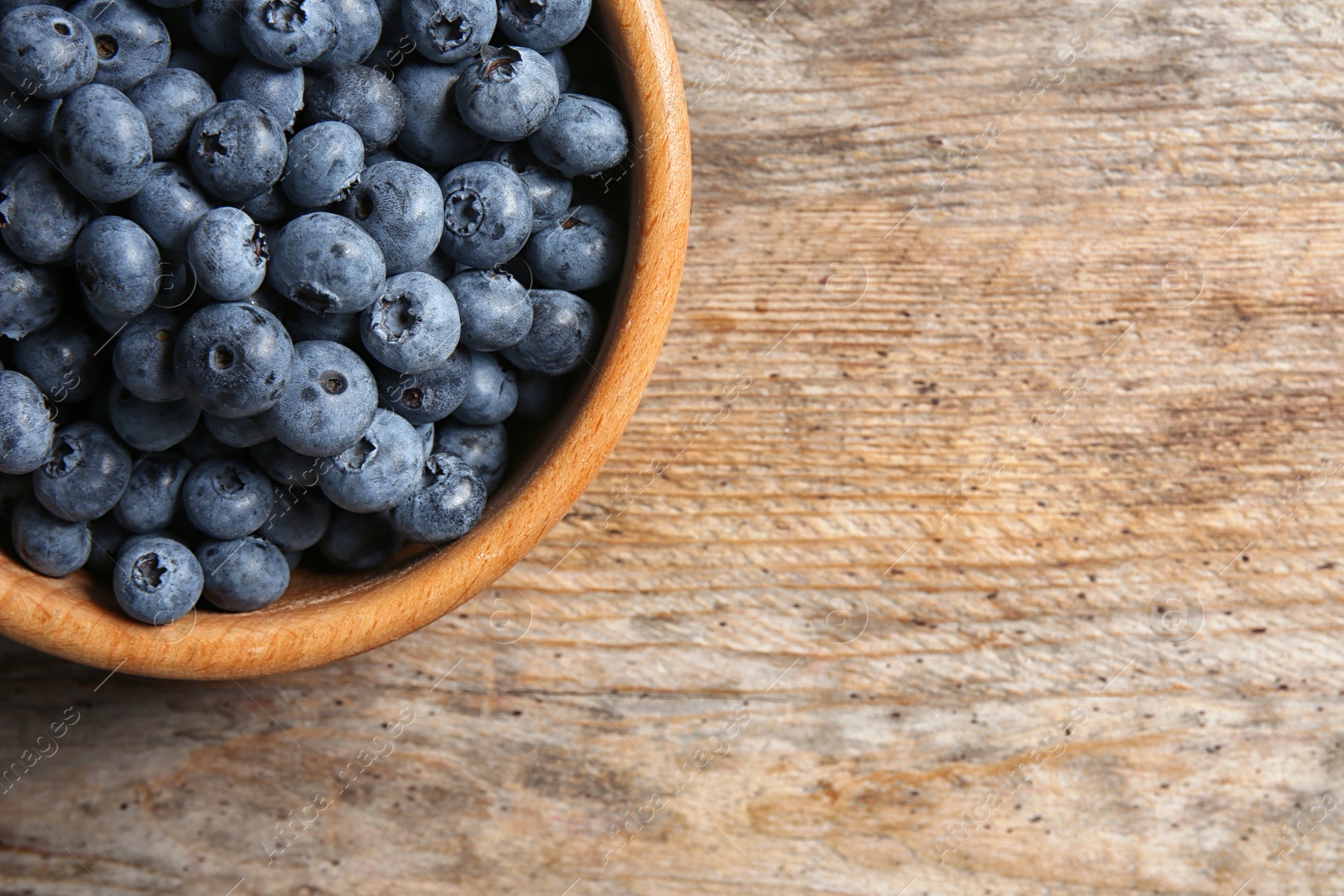 Photo of Dishware with fresh blueberries and space for text on wooden table, top view