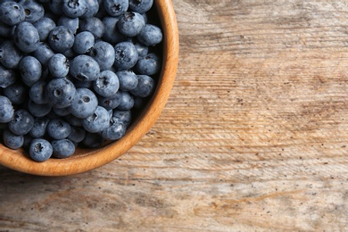 Photo of Dishware with fresh blueberries and space for text on wooden table, top view