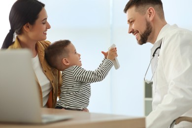 Photo of Mother and son visiting pediatrician in hospital. Doctor playing with little boy