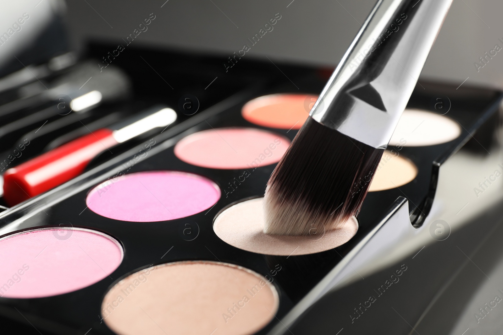 Photo of Colorful eyeshadow palette with brush on grey background, closeup