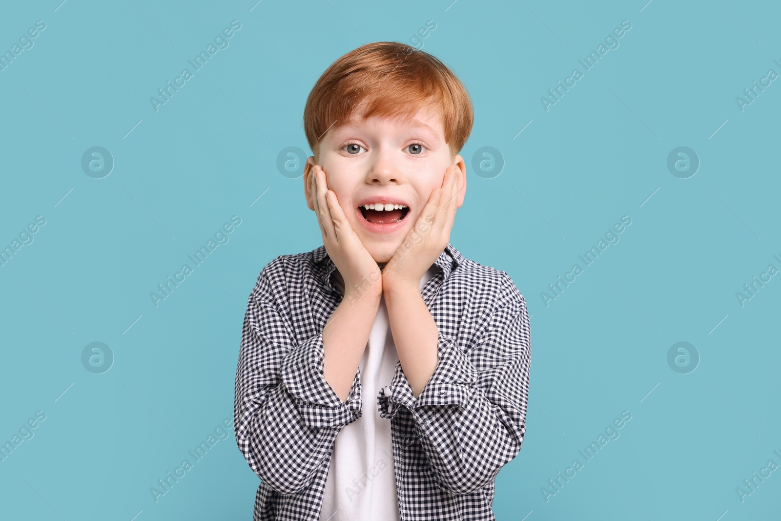 Photo of Surprised little boy on light blue background