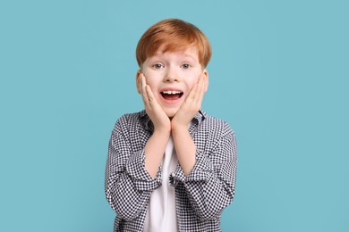 Surprised little boy on light blue background